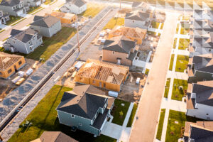 Vista aérea de loteamento residencial em desenvolvimento, com casas prontas e outras em construção ao longo de ruas pavimentadas.